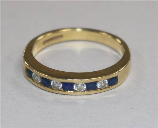 A modern 18ct gold and nine stone sapphire and diamond half hoop ring, size N.